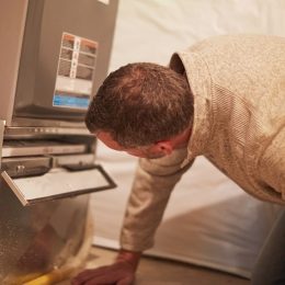 HVAC technician inspecting furnace filter slot on a furnace