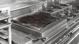 Commercial stainless steel kitchen stove with grill grate and gas burners (professional kitchen).