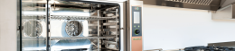 Commercial convection oven with stainless steel interior and racks visible through a glass door on the left, and a vertical control panel on the right.