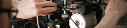 Hands of a technician tightening a red-topped control on an industrial pump with a screwdriver in a workshop setting rail